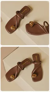 Détail de sandales à entredoigt marron avec ornement boule dorée et lanières croisées
