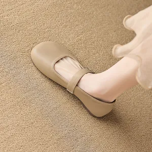Classic khaki Mary Jane flat shoes with round toe and strap shown on a beige carpet