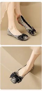 Detailansicht der flachen Leopard-Schuhe mit schwarzer Schleife und goldener Kette