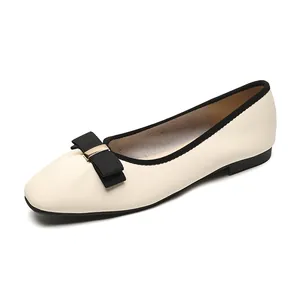 Elegante beige flache Schuhe mit schwarzer Schleife und goldener Schnalle in 45-Grad-Ansicht