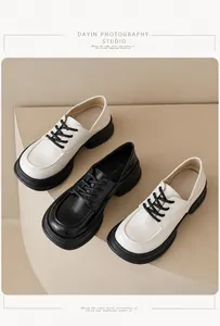 Close-up of platform leather loafers in black and cream beige with lace-up closure detail