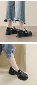 Dettaglio di mocassini platform in vernice nera abbinati a jeans a zampa blu