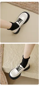 Close-up of beige platform loafers with black laces and thick rubber soles worn with socks