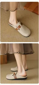 Dettaglio di sabot beige a punta chiusa con fibbia in pelle marrone e suola piatta nera