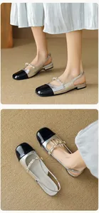 Detail of silver slingback flats with black patent toe and elegant pearl strap decoration