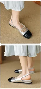 Detailed view of silver Mary Jane flats with black patent toe and pearl strap accent
