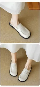 Detailed view of beige leather flat mule loafers with elegant cross-stitch stitching