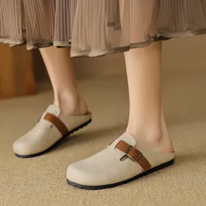 Sabot beige a punta tonda con cinturino in pelle marrone indossati da modella