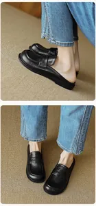 Detailed views of black leather mule loafers showing the round toe and slip-on flat design