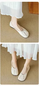 Close-up of pleated round toe flats in cream soft leather with a minimalist vintage style