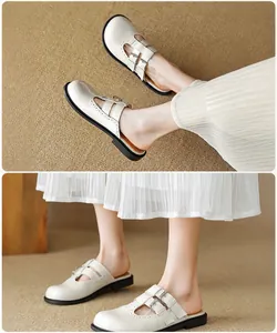 Detail of off-white Mary Jane mules with dual buckled straps and brogue style perforations