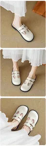 Close-up of cream-colored brogue mule slippers with double straps and cutout details