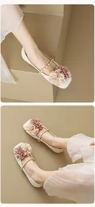 Close-up of square toe flat shoes with floral decor and a gold chain strap