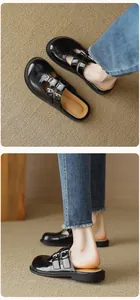 Detail view of black patent leather Mary Jane mules with double buckle and T-strap design