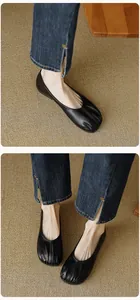 Macro shot of black pleated round toe ballet flats worn with denim jeans for a vintage look