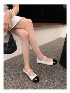 Detail der Mary Jane Ballerinas mit schwarzer Kappe und weißem Leder mit Perlenarmband
