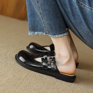 Glossy black patent leather Mary Jane mules with double silver buckles on denim background