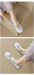 Detail von silbernen Satin-Mary-Jane-Ballerinas mit Schleife und goldener Schnalle