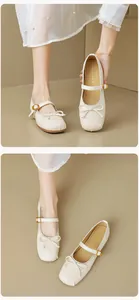 Detail von cremefarbenen Mary Jane Ballerinas mit Schleife und goldener Schnalle