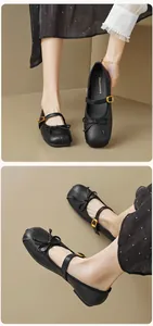 Details von schwarzen matten Leder-Ballerinas mit Schleife und goldener Schnalle