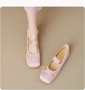 Détail de ballerines en satin rose avec un nœud délicat et une bride élastique de maintien