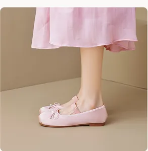 Détail de ballerines en satin rose avec nœud et bride élastique sur le modèle