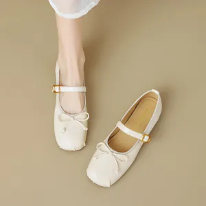 Ballerine Mary Jane beige con fiocco e fibbia dorata su sfondo a tinta unita