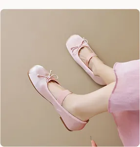 Détail de ballerines en satin rose avec nœud et bride élastique en vue latérale