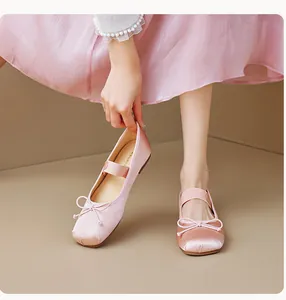 Détail de ballerines en satin rose clair avec nœud et bride élastique élégante