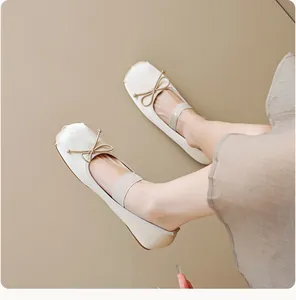 Gros plan sur des ballerines en satin crème avec nœud délicat et bride élastique