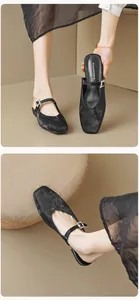Detailed macro view of black square-toe mule sandals with sparkling rhinestone buckle