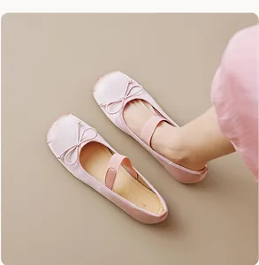 Gros plan sur les ballerines en satin rose avec nœud et bride élastique aux pieds