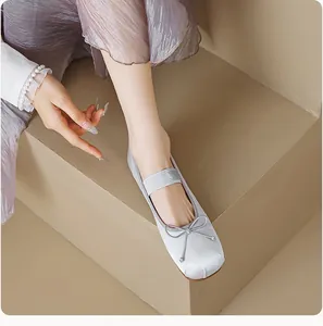 Vue de dessus de ballerines en satin gris clair avec nœud et bride élastique sur modèle