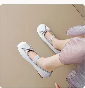 Gros plan de ballerines en satin argenté avec nœud et bride élastique sur modèle