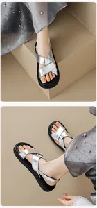 Detail of silver metallic cross-strap sandals with thick black soles and elastic heel