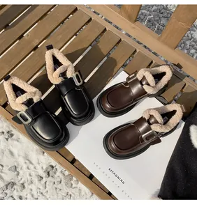 Detalle de mocasines con plataforma negros y marrones con forro cálido de lana y hebilla de metal