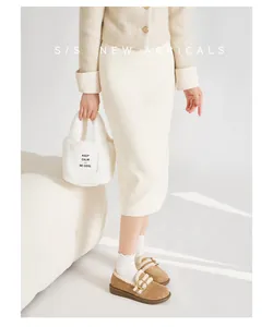 Nahaufnahme brauner Plüsch-Loafer mit weißen Spitzensocken und einer Pelz-Tragetasche