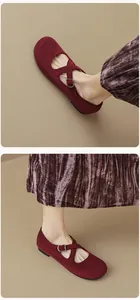 Close-up of burgundy suede Mary Jane flats with crisscross straps and metal buckles