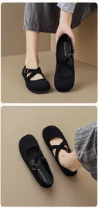 Close-up of black suede Mary Jane ballet flats with crossover straps and metal buckles
