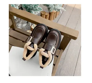 Primer plano de mocasines marrones con plataforma, forro de felpa y hebilla de metal plata