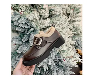 Detalle de mocasín marrón con plataforma, forro de piel de oveja y hebilla plateada