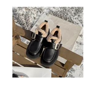 Primer plano de mocasín negro con plataforma, forro de pelo blanco y hebilla de metal