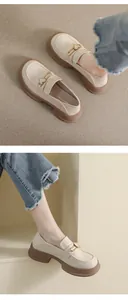 Detail of cream platform loafers with golden heart buckles and thick brown rubber soles