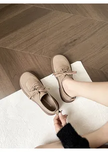 Detailed top view of khaki suede round-toe lace-up shoes on textured wood flooring