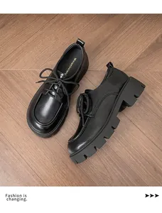 Detail of black thick platform derby shoes with lug sole and lace-up design on wood floor