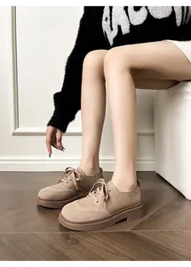 Detail of khaki suede platform derby shoes with thick soles and lace-up design on wood