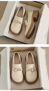Detail of cream platform loafers featuring golden heart buckles and brand logo insoles