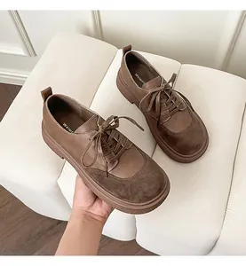 Detail view of brown leather and suede patchwork loafers with thick soles and laces