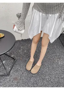 Beige suède loafers gecombineerd met een grijze trui en een witte satijnen rok
