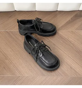 Detail of black platform derby shoes with lug soles on a vintage herringbone wood floor